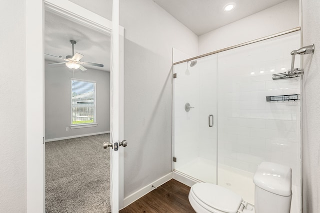 bathroom featuring wood-type flooring, ceiling fan, a shower with door, and toilet