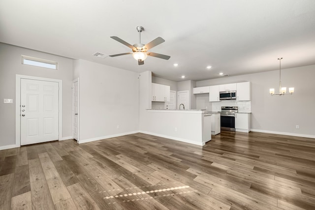 unfurnished living room featuring ceiling fan with notable chandelier and dark hardwood / wood-style floors