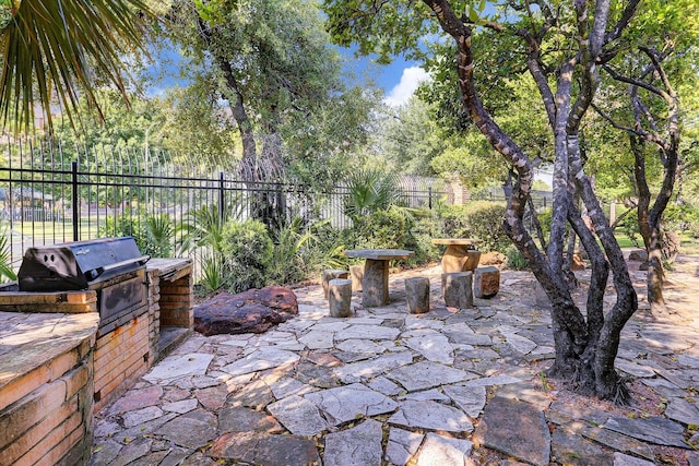 view of patio featuring an outdoor kitchen, fence, and a grill
