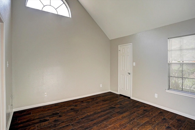 spare room with baseboards, a wealth of natural light, dark wood-style flooring, and lofted ceiling