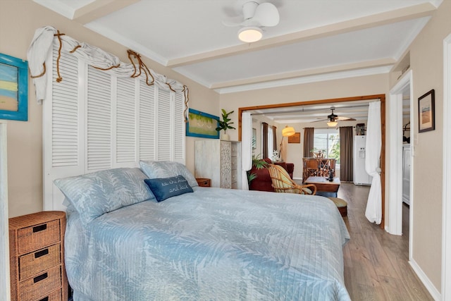 bedroom featuring hardwood / wood-style flooring, white refrigerator with ice dispenser, and a closet