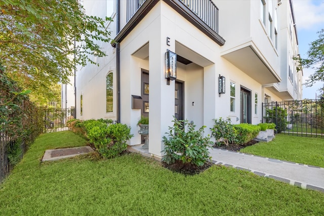 view of exterior entry with a yard and a balcony