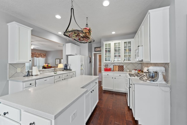 kitchen with white appliances, dark wood-type flooring, sink, white cabinets, and a center island