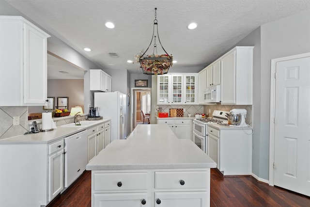 kitchen featuring white appliances, a kitchen island, decorative light fixtures, dark hardwood / wood-style floors, and white cabinets