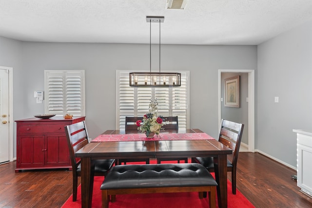 dining area featuring dark wood-type flooring, a notable chandelier, and a textured ceiling