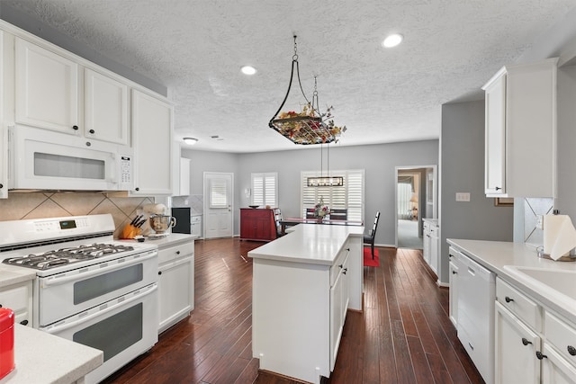 kitchen with a center island, dark wood-type flooring, white appliances, and decorative light fixtures