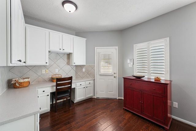 kitchen with plenty of natural light, built in desk, white cabinetry, and dark hardwood / wood-style floors