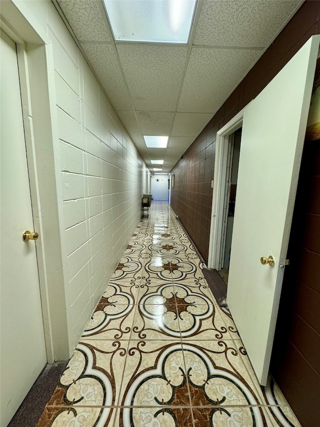 corridor featuring a drop ceiling and light tile patterned flooring