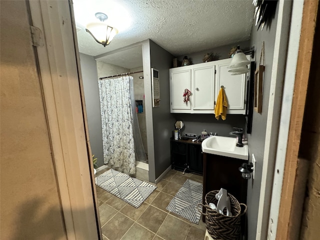 bathroom featuring tile patterned flooring, walk in shower, vanity, and a textured ceiling