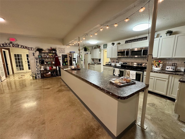 kitchen featuring a kitchen island, decorative backsplash, stainless steel appliances, white cabinetry, and a textured ceiling