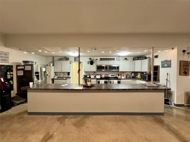 kitchen featuring a large island, backsplash, white cabinetry, appliances with stainless steel finishes, and dark stone counters