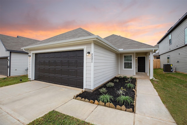 ranch-style house with a lawn, cooling unit, and a garage