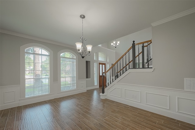 entrance foyer with a chandelier, hardwood / wood-style floors, and crown molding