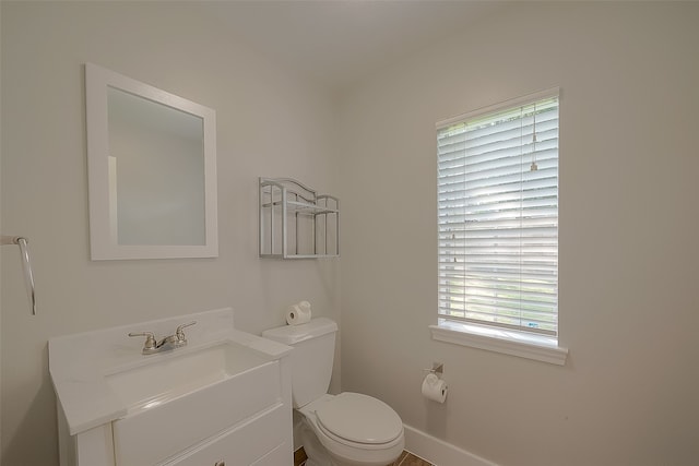 bathroom with plenty of natural light, toilet, and vanity