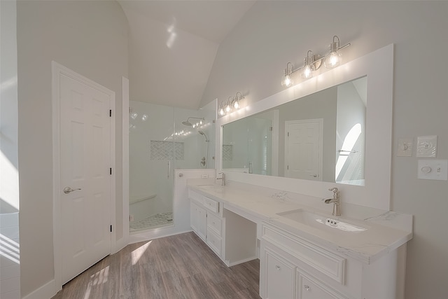 bathroom featuring wood-type flooring, vaulted ceiling, vanity, and a tile shower