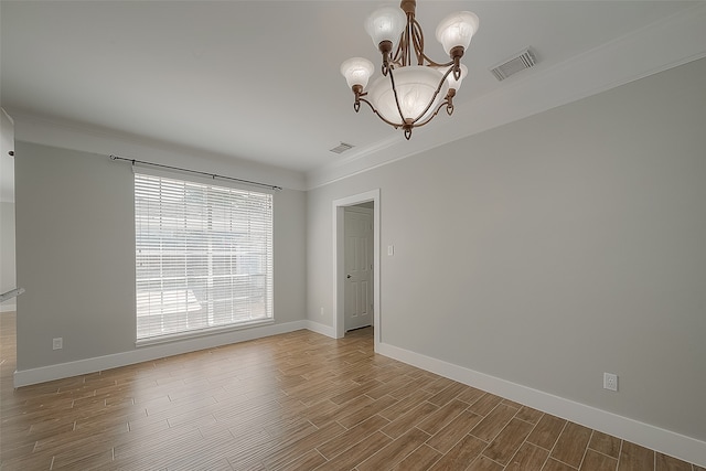 spare room with a healthy amount of sunlight, crown molding, hardwood / wood-style floors, and an inviting chandelier