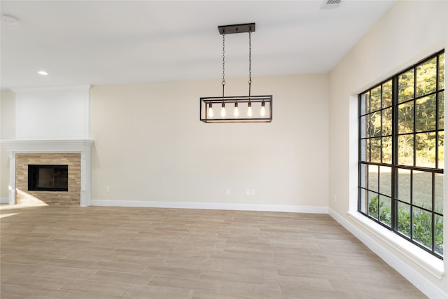 interior space featuring light hardwood / wood-style flooring, a tiled fireplace, and a wealth of natural light