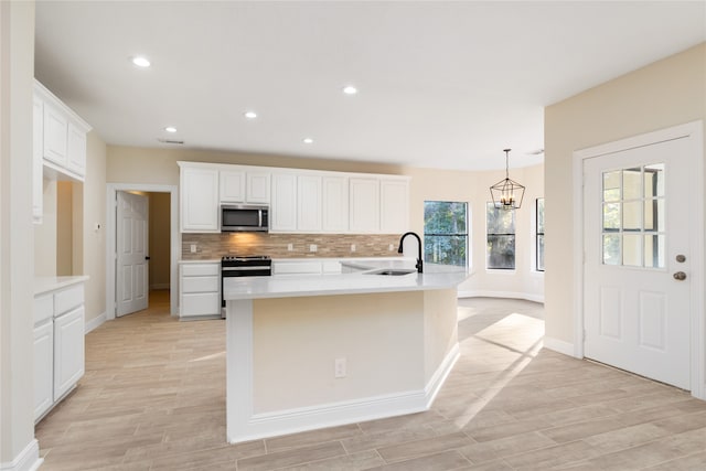 kitchen featuring a center island with sink, sink, white cabinetry, and stainless steel appliances