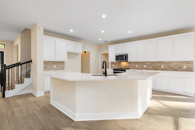 kitchen with appliances with stainless steel finishes, light hardwood / wood-style flooring, a spacious island, and white cabinetry