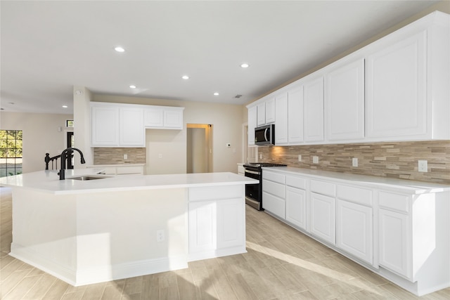 kitchen featuring sink, appliances with stainless steel finishes, light wood-type flooring, and white cabinetry