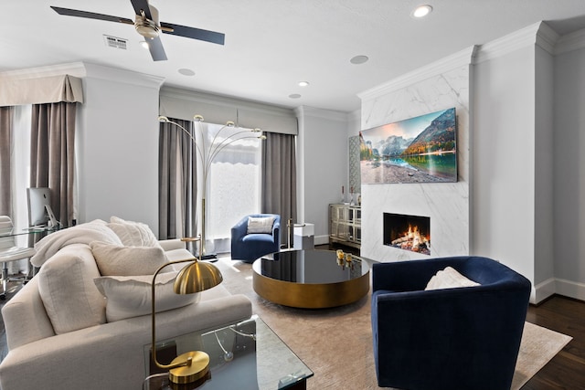 living room featuring ceiling fan, a high end fireplace, crown molding, and dark hardwood / wood-style floors