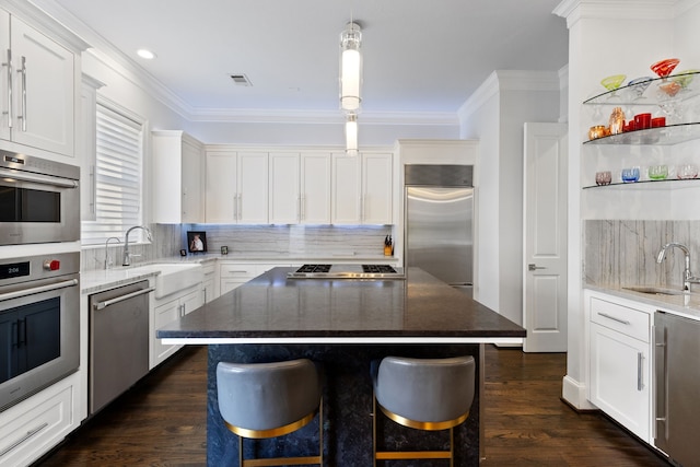 kitchen featuring hanging light fixtures, a kitchen island, appliances with stainless steel finishes, dark hardwood / wood-style floors, and dark stone countertops