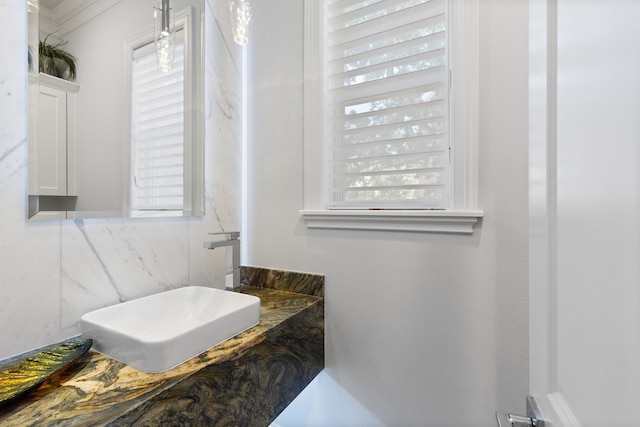 bathroom with ornamental molding, a healthy amount of sunlight, vanity, and tile walls