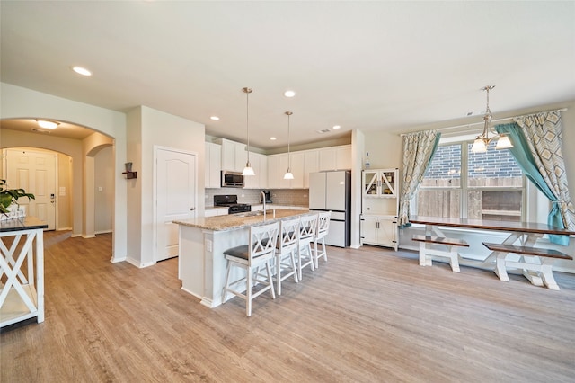 kitchen featuring white refrigerator, pendant lighting, gas stove, light hardwood / wood-style flooring, and white cabinets