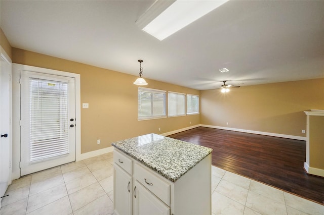 kitchen featuring decorative light fixtures, light tile patterned floors, a kitchen island, a wealth of natural light, and white cabinets