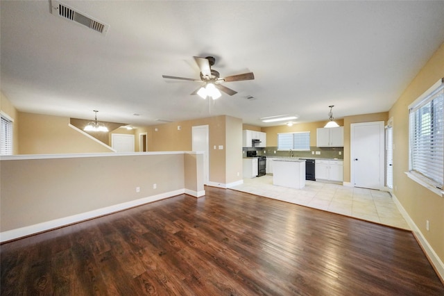 unfurnished living room featuring ceiling fan with notable chandelier, sink, and light hardwood / wood-style floors