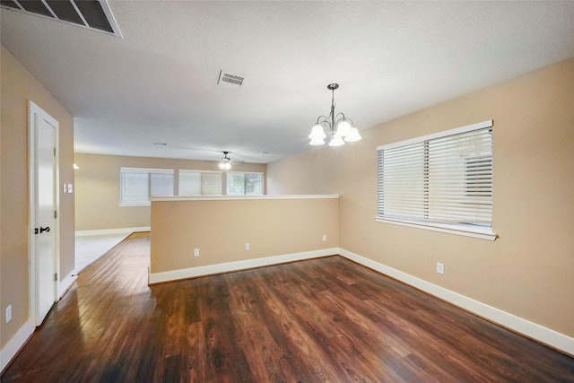 unfurnished room featuring dark hardwood / wood-style floors, ceiling fan with notable chandelier, and a textured ceiling