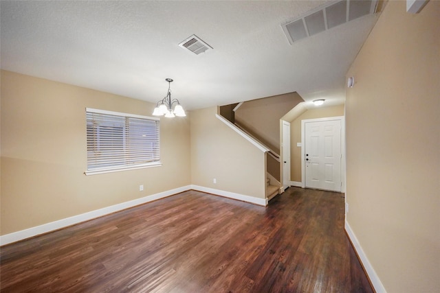 empty room featuring dark wood-type flooring and a notable chandelier