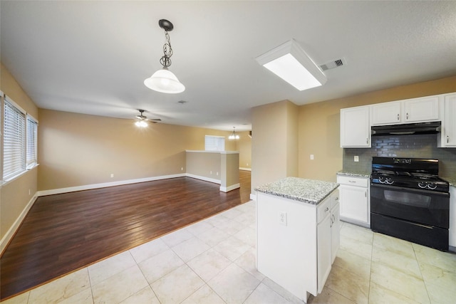 kitchen featuring a kitchen island, decorative light fixtures, white cabinets, backsplash, and black gas range