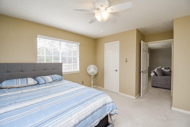 bedroom featuring a textured ceiling, baseboards, a ceiling fan, and light colored carpet