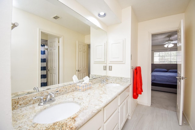 ensuite bathroom with connected bathroom, a sink, baseboards, and double vanity