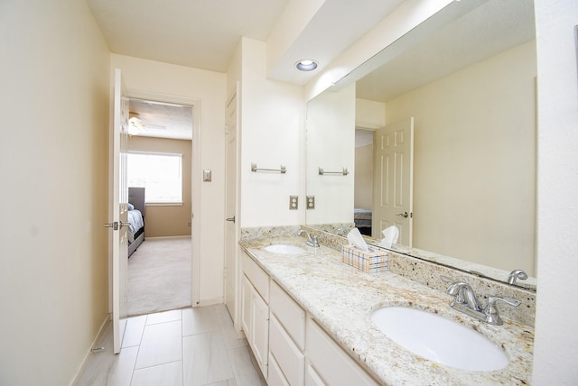 full bathroom featuring baseboards, connected bathroom, a sink, and double vanity