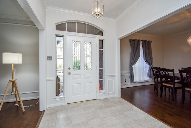 foyer with crown molding and light wood finished floors