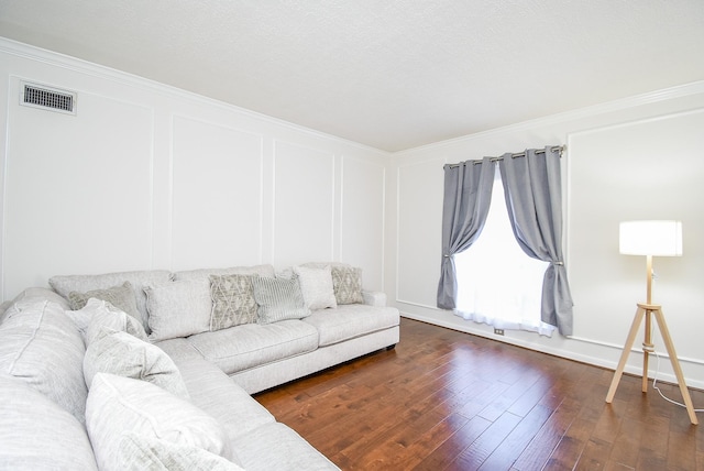 living room featuring ornamental molding, dark wood finished floors, visible vents, and a decorative wall