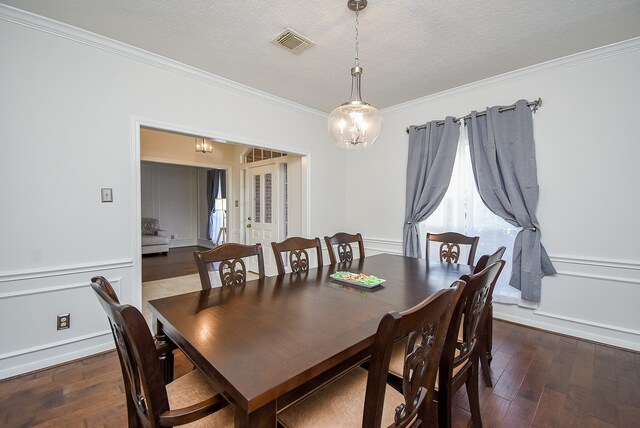 dining space featuring ornamental molding, a textured ceiling, a notable chandelier, and dark hardwood / wood-style floors