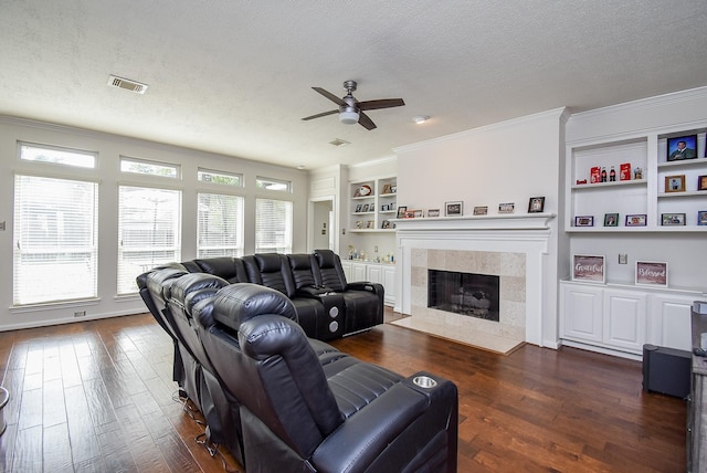 living area with built in features, crown molding, visible vents, dark wood-type flooring, and a textured ceiling