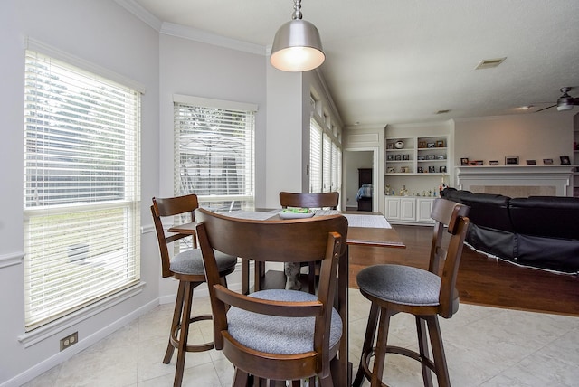 dining area with light tile patterned floors, built in shelves, visible vents, baseboards, and ornamental molding