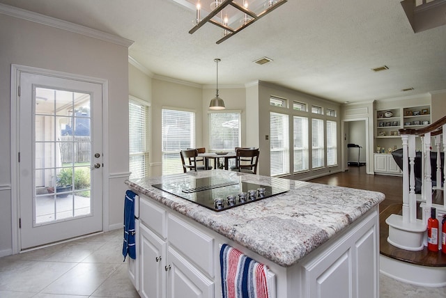 kitchen with a kitchen island, open floor plan, black electric cooktop, white cabinetry, and pendant lighting