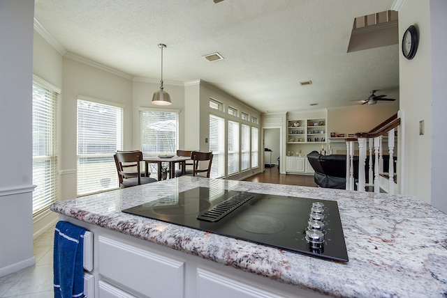 kitchen with a wealth of natural light, black electric stovetop, and decorative light fixtures