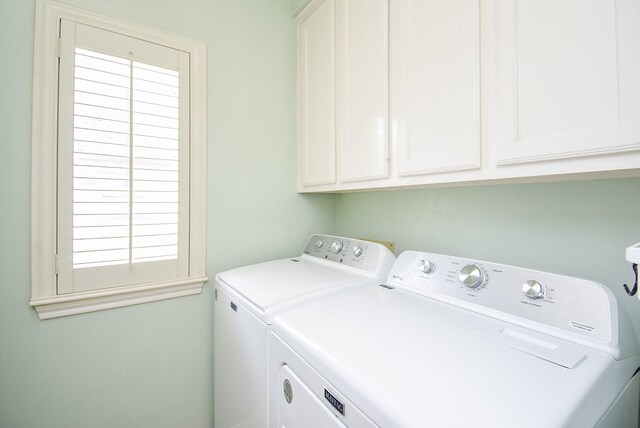 laundry room with cabinets, a healthy amount of sunlight, and separate washer and dryer