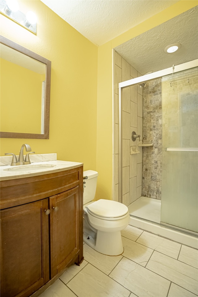 bathroom with toilet, tile patterned floors, a shower with door, vanity, and a textured ceiling