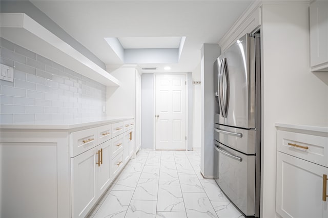 kitchen featuring a raised ceiling, backsplash, stainless steel fridge with ice dispenser, and white cabinetry