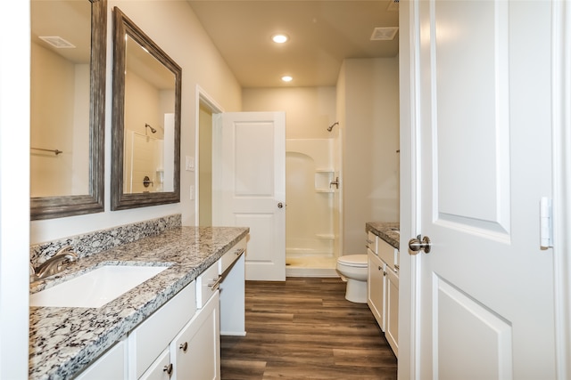 bathroom with a shower, hardwood / wood-style flooring, vanity, and toilet