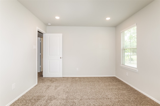 unfurnished room with light colored carpet and a wealth of natural light