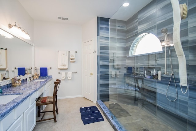 bathroom featuring tile patterned flooring, vanity, and a tile shower