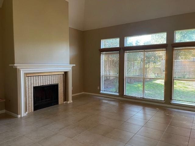 unfurnished living room with a fireplace, light tile patterned floors, and a high ceiling